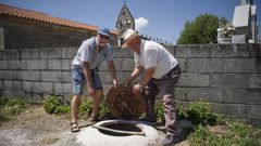 Secundino Castro y Severo Palomanes, vecinos de la aldea de Garabelos, miran las arquetas de los dep�sitos para comprobar si tienen agua