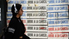 Una mujer pasa cerca de varios carteles, colocados en la ciudad de Bogot, en los que se pide la entrada en prisin del expresidente lvaro Uribe.