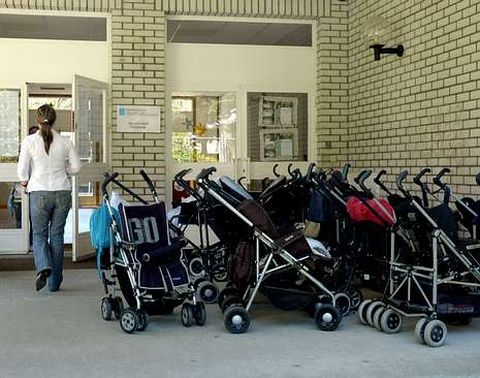 Una mujer pasa ante los carritos aparcados a las puertas de una guardera pblica de la ciudad.