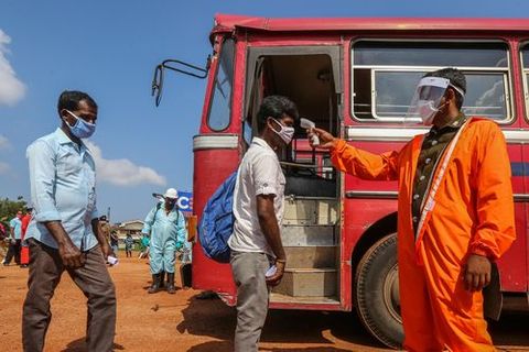 Un hombre toma la temperatura a los que suben al autob�s en Sri lanka