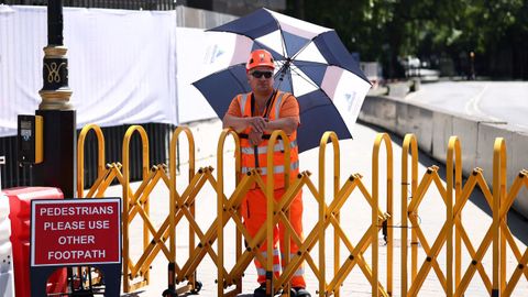 Un trabajador se protege del sol bajo un paraguas en Londres (Reino Unido).