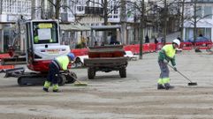 Operarios este viernes sobre la plaza disponiendo material con cepillos para tapar los surcos.