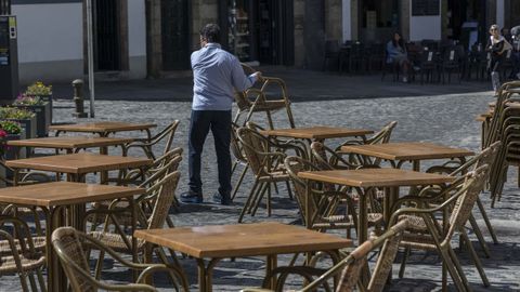 Un camarero recoge las sillas de una terraza en Santiago de Compostela.