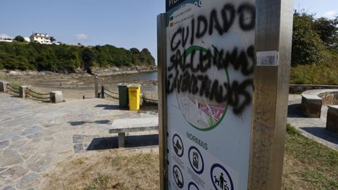 El cartel de la playa de Seiramar, en Covas, donde se recuerdan las normas que fija la ordenanza ha sido objeto de vandalismo