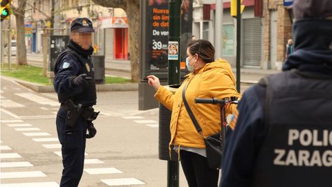 Un polic�a habla con una mujer protegida con mascarilla durante el estado de alarma, en Zaragoza 