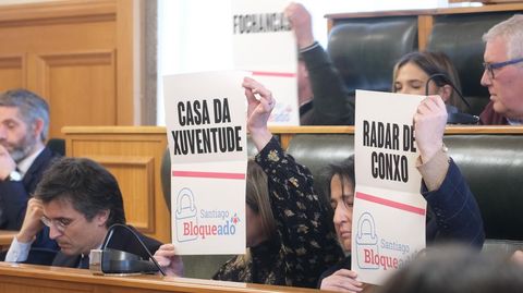 Concejales del PP muestran carteles con sus propuestas durante el pleno del Concello de Santiago sobre el estado del municipio