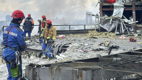 Imagen proporcionada por el Servicio Estatal de Emergencias que muestra a rescatistas ucranianos trabajando en el lugar de un ataque con cohetes en Kiev.