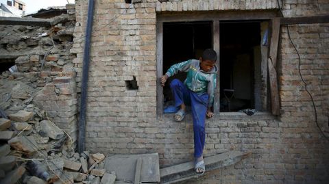 Un niño sale por la ventana de su casa en Katmandú.