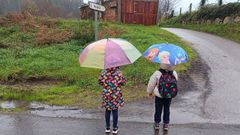 Dos de los alumnos transportados, esta lluviosa maana de jueves esperando el bus en Merille
