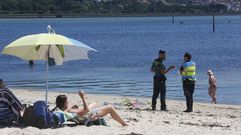 Un polic�a local y un guardia civil custodiando el cad�ver de la fallecida, en el arenal de Lourido.