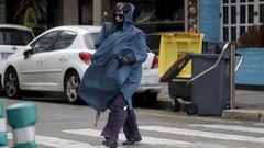 Una mujer camina envuelta en un chubasquero por A Coru�a