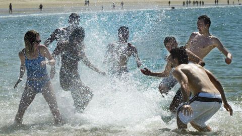 Jovenes baandose en la playa de Samil,disfrutando del buen tiempo con una batalla de agua en 2003.