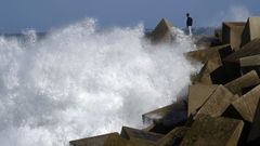 Una persona contempla de cerca las olas rompiendo en el rompeolas del espig�n del puerto de Cudillero este s�bado.