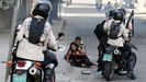 Agentes de seguridad rodean a dos manifestantes afectados por un ataque con bombas lacrim�genas
