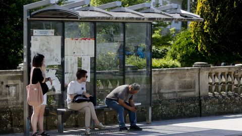 Imagen de tres lucenses esperando un bus urbano.