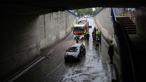 Efectivos del cuerpo de bomberos socorren a un veh�culo que se ha quedado atrapado en un cruce bajo la A-5, en Madrid