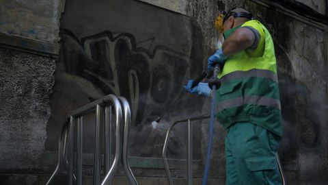 Un trabajador limpiando una pintada en la zona de A Gaiteira