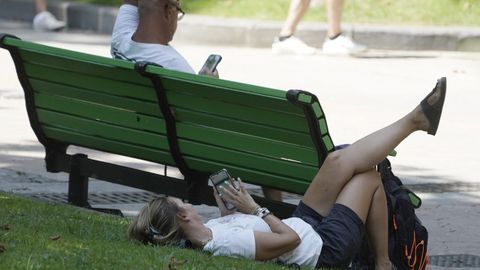 Una mujer tumbada sobre el c�sped este viernes, en el parque de San Francisco (Asturias)