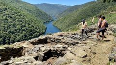 Uno de los investigadores, este lunes en el yacimiento de Os Conventos con dos vecinas de la zona