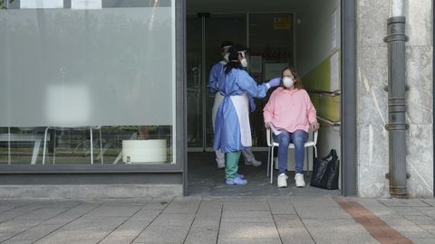 Dos sanitarios protegidos con guantes, mascarillas y pantallas protectoras recogen una muestra de una trabajadora en Bilbao