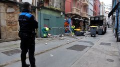 Un polic�a local de A Coru�a vigilando ayer la actividad de los operarios de la basura en el Orz�n.
