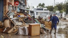 Varias personas quitan el barro de las calles mientras se acumula el mobiliario que han tenido que sacar debido a las inundaciones por las fuertes lluvias