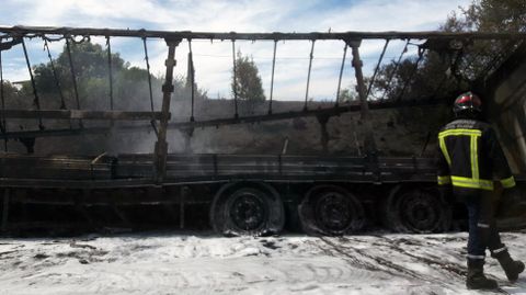 Un bombero pasa delante del cami�n calcinado, en el arcen de la autopista Y.Un bombero pasa delante del cami�n calcinado, en el arcen de la autopista Y