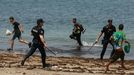 Polic�as nacionales tratan de controlar a un grupo de inmigrantes en la costa de Ceuta.