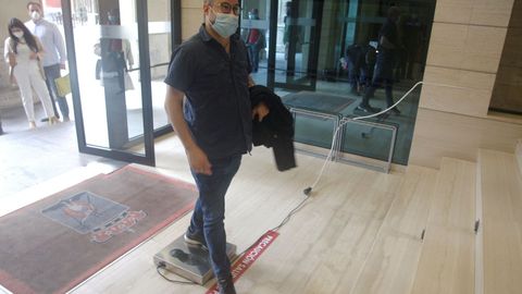 Un ciudadano entra en el Ayuntamiento de Gij�n con mascarilla y tras utilizar un nuevo sistema para descontaminar zapatos de COVID-19