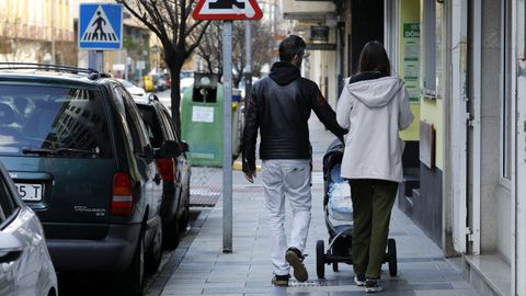 Una joven pareja pasea por las calles de Ribadeo empujando el carrito de un beb&eacute;.