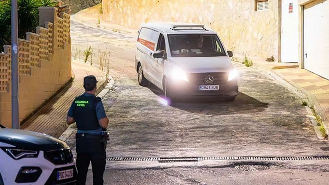 Un guardia civil observa la salida del furg�n con los dos cad�veres, y una foto de la mujer fallecida