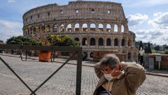 Un turista coloc�ndose una m�scara frente al Coliseo de Roma casi desierto