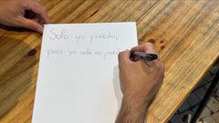 El testimonio, escribiendo en un papel el lema de Agaja