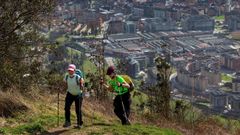 Dos senderistas subiendo al monte Naranco con Oviedo al fondo