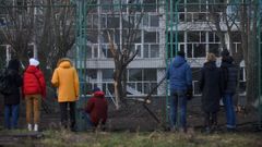 Varias personas miran el cr�ter provocado por un bombardeo ruso en un estadio de Kiev