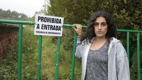 La propietaria de Tropic Gaia, Andrea González, en la entrada de la finca con el cartel que le obligó a colocar la Xunta