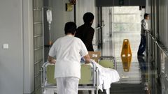 Una celadora traslada a un enfermo que fue ingresado en el hospital