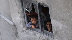 Un nio y una mujer miran por la ventana en una vivienda de la ciudad de Gaza