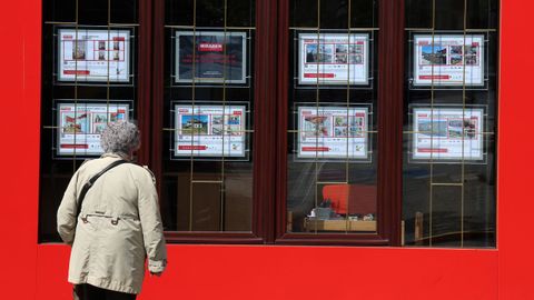 Una mujer consulta anuncios de pisos en venta en una inmobiliaria de Boiro.