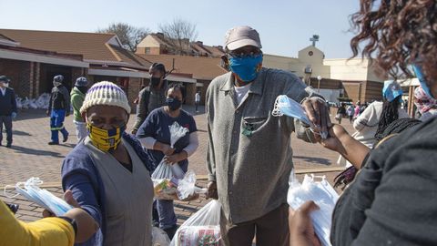 Ciudadanos con mascarilla reciben ayuda durante la pandemia en Soweto, Sud�frica