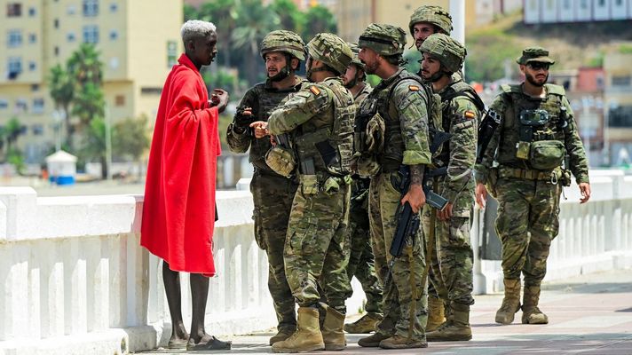 Soldados del ej&eacute;rcito espa&ntilde;ol dialogan con uno de los inmigrantes llegados a Ceuta de forma ilegal desde Marruecos.