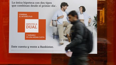 Imagen de archivo de un transe�nte delante de un cartel promocional con una oferta hipotecaria.