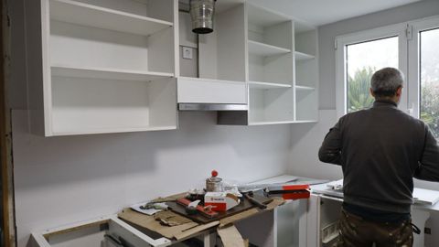 Un carpintero trabajando en la reforma de una cocina. 