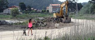 Una excavadora est� realizando ya los trabajos para dibujar el nuevo trazado de la pista que da acceso a la planta. 