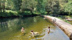 Una familia de turistas catalanes disfrutando de la playa fluvial de A Calzada