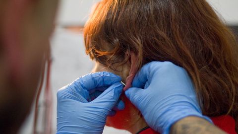 Imagen de archivo de una mujer mientras le hacen un piercing. 