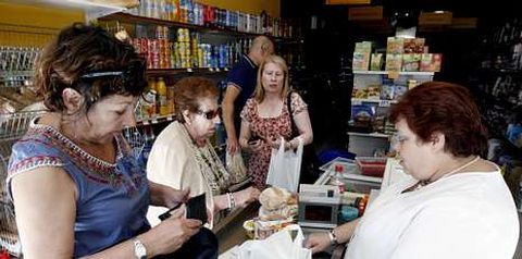 A propietaria da tenda cobrando aos clientes durante o apag�n el�ctrico, a caixa rexistradora non funcionaba.