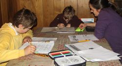 Haciendo tareas en casa ante la mirada atenta de la madre