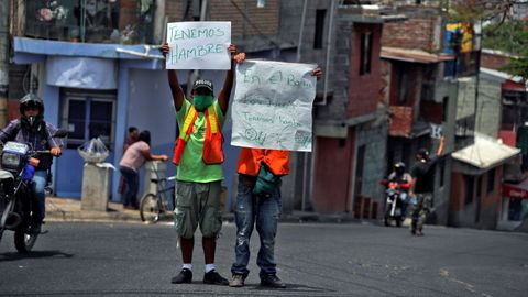 Dos hombres piden dinero y comida mientras sostienen carteles en los que informan su situacin de pobreza en Tegucigalpa, Honduras