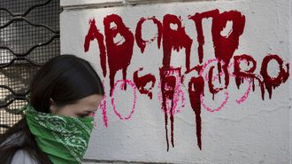 Una mujer pasa frente a un muro con el mensaje 'Aborto Seguro' durante el 8M del 2026, en Chile